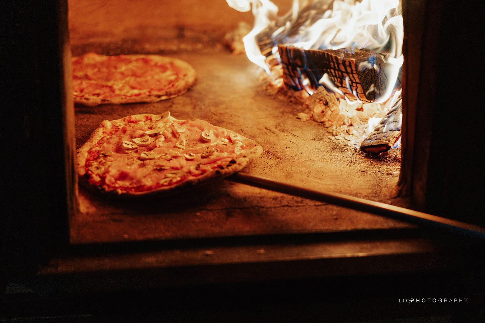 Napolitaanse pizza bakt in de houtoven van Pizza Pelgrims, met vlammen op de achtergrond