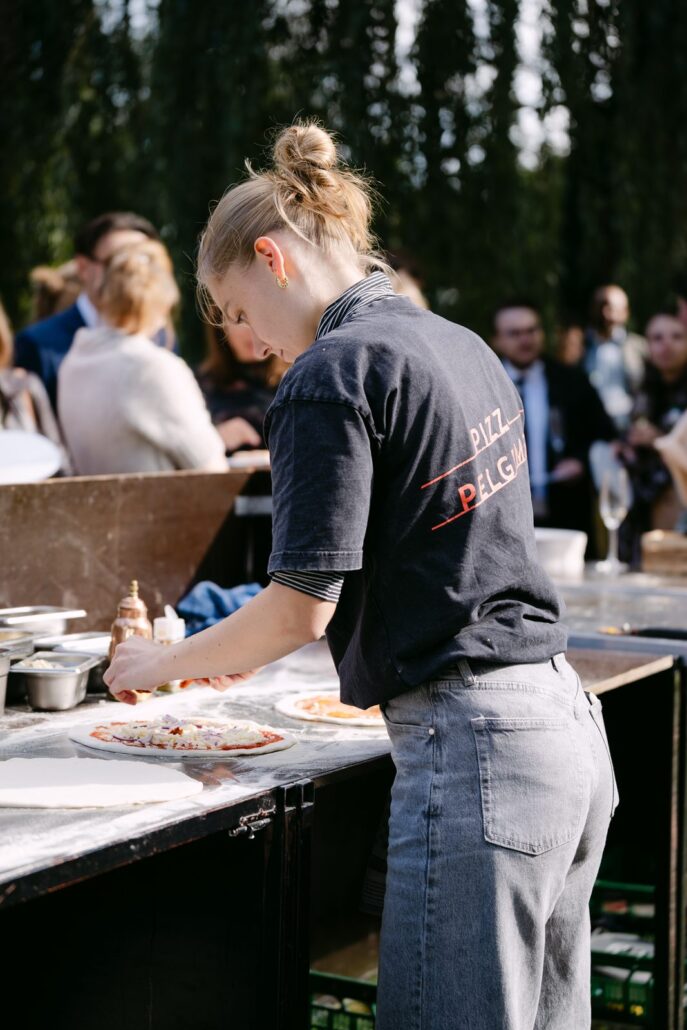 Pizzaiola van Pizza Pelgrims belegt een pizza tijdens een feest