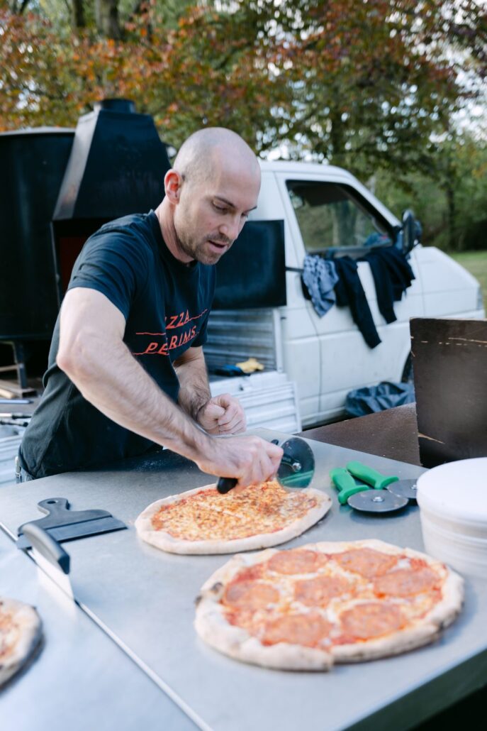 Versgebakken houtovenpizza's worden gesneden aan de toog van Pizza Pelgrims