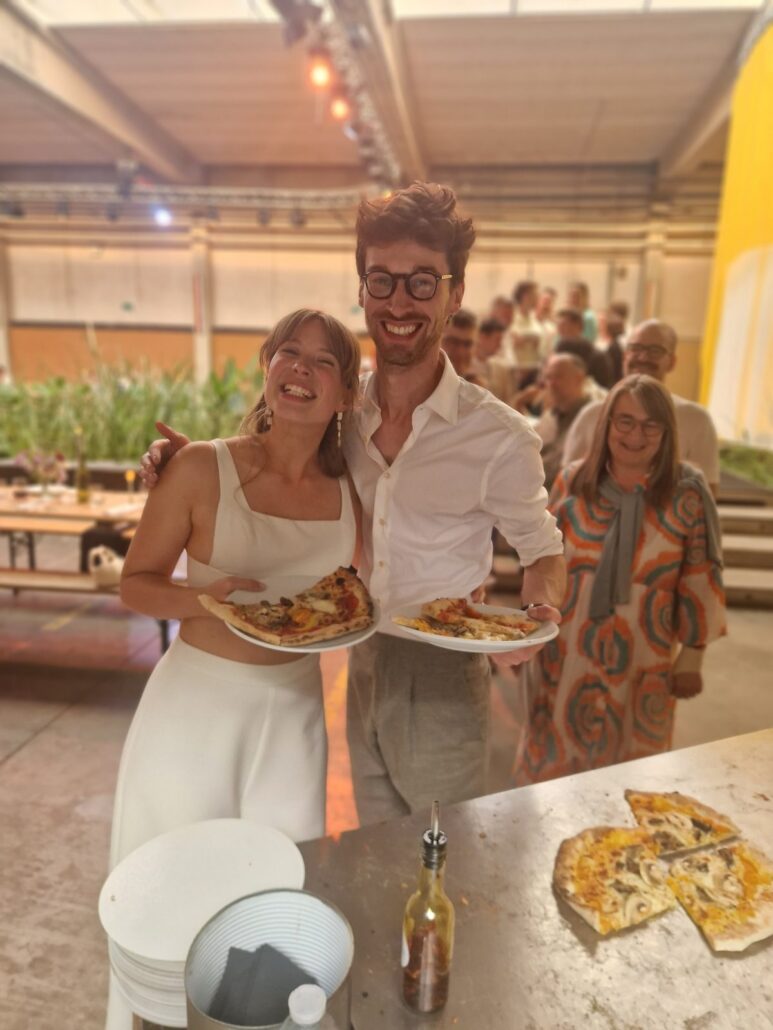 Lachend koppel met pizza van Pizza Pelgrims op een trouwfeest